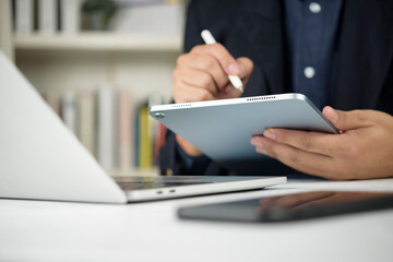 Businessman hand using digital tablet stylus pen writing screen office desk laptop computer smartphone. Corporate professional working online technology internet wireless concept.