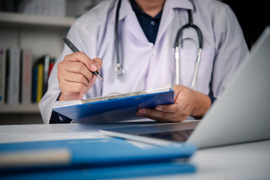 Doctor hand writing medical report clipboard hospital office desk. Physician checking patient chart diagnosis using pen. Healthcare professional insurance prescription concept.