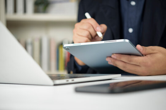 Businessman hand using digital tablet stylus pen writing screen office desk laptop computer smartphone. Corporate professional working online technology internet wireless concept.