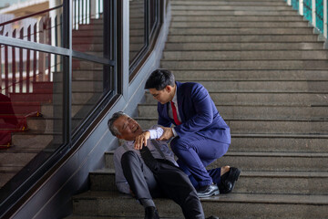 A young businessman in a suit supports and helps a senior colleague stand, reflecting intergenerational teamwork, empathy, and collaboration in a modern, innovative business environment