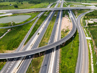 Drone shot a large highway interchange crossing over green farmlands in Thailand