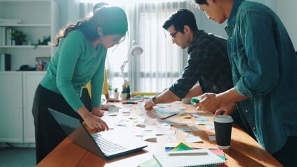 Skilled business team looking at laptop and pointing logo design while making decision to choosing...