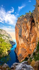 Dramatic, high-angle view of a blue inlet bordered by tall, rocky cliffs covered in greenery