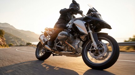 Motorcyclist riding a sleek adventure bike on a scenic mountain road during sunset