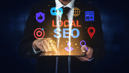 A businessman interacts with a tablet displaying dynamic icons representing local SEO strategies. The dark background enhances the vibrant visuals, reflecting digital marketing concepts. Gantry