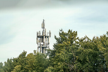 Towering above the trees, a communications tower reaches toward the sky on a bright day in the countryside