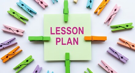Colorful clothespins arranged around a light green sticky note with the words lesson plan written in pink text Background image