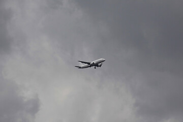 Airplane descending through dark storm clouds with landing gear deployed, highlighting dramatic weather, flight preparation, and atmospheric tension in the sky