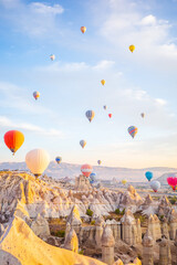 A breathtaking sunrise scene in Cappadocia, Turkey, showing colorful hot air balloons drifting gracefully above the region&rsquo;s iconic fairy chimneys and dramatic rock formations