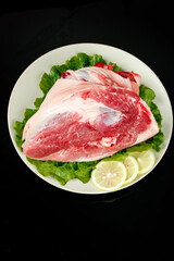 Premium Raw Pork Elbow Steaks on Fresh Greens with Lemon