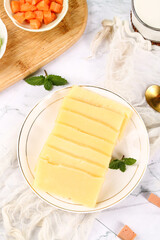 Sliced German Cheese Block on Plate with Fresh Mint