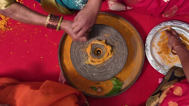 Group of Indian women holding a stone peace of mortar for making turmeric paste for wedding ceremony. Its a rituals of traditional Hindu wedding, Haldi ceremony