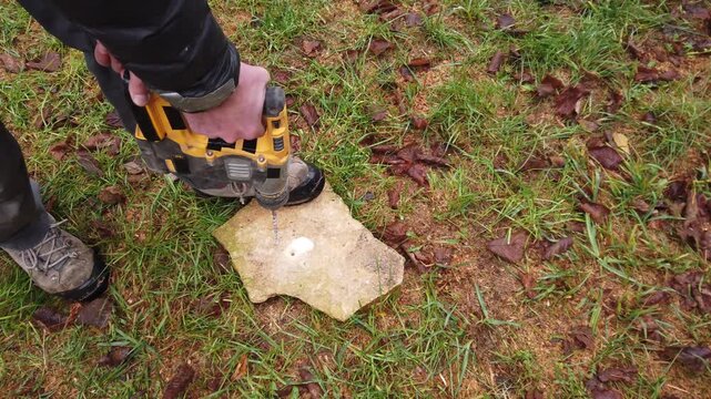 Hands of worker working on natural stone with cordless SDS rotary hammer drill 