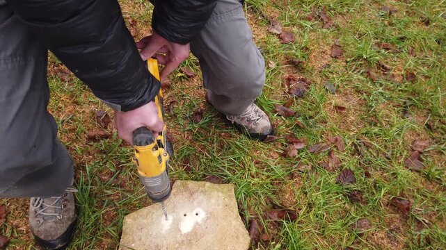 Hands of worker working on natural stone with cordless SDS rotary hammer drill 