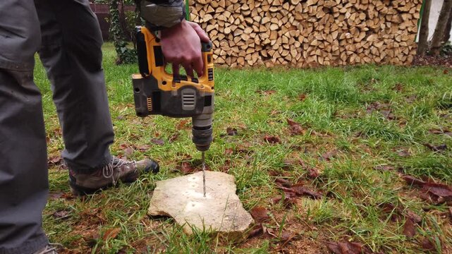 Hands of worker working on natural stone with cordless SDS rotary hammer drill 