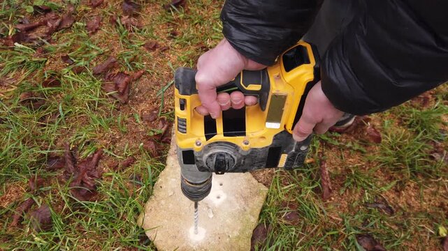 Hands of worker working on natural stone with cordless SDS rotary hammer drill 