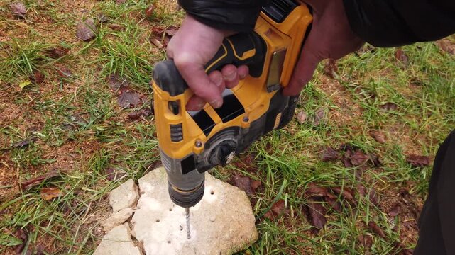 Hands of worker working on natural stone with cordless SDS rotary hammer drill 