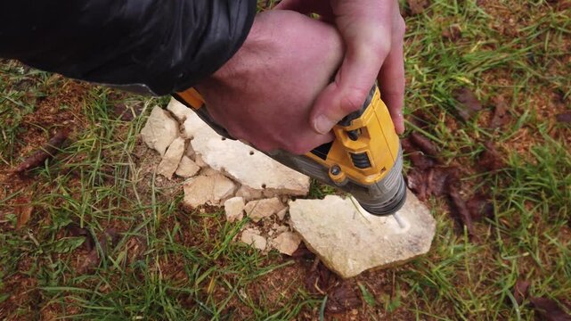 Hands of worker working on natural stone with cordless SDS rotary hammer drill 