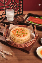Handmade Scallion Pancakes in Basket with Traditional Breakfast Setup on Wooden Table