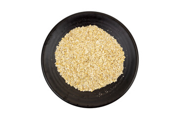 Top-down view of dry rolled oats or instant oatmeal flakes served on a black ceramic plate, isolated on a white background. This image represents healthy breakfast, grains, and raw food ingredients.