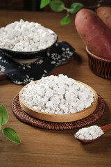 Raw Potato Starch Flour in Wooden Bowls with Fresh Sweet Potatoes on Rustic Kitchen Table