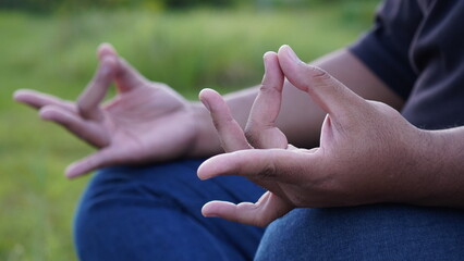 A person performing the Gyan Mudra hand gesture outdoors, symbolizing knowledge, concentration, and meditation