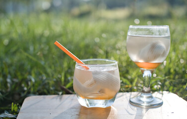 Coconut perfume water mixed with wild honey in a glass on a wooden floor in the grass warm morning light.