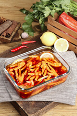 Fresh Spicy Chicken Feet Marinated in Red Sauce with Lemon and Herbs on Wooden Table