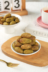 Green olives and dried fruit on wooden board with tea cup in modern kitchen