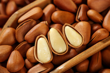 Obraz premium Hand-peeled pine nuts with open shells revealing white kernels, natural healthy food ingredient