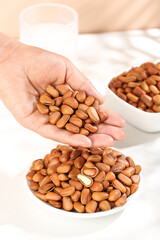 Fresh Pine Nuts in Hand with Bowls of Handpeeled Nuts on Kitchen Counter