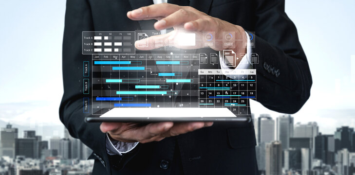 A businessman engages with a transparent virtual interface displaying project management data against a city skyline backdrop, symbolizing innovation in business solutions. Gantry