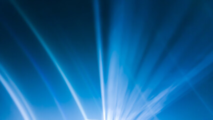 Dramatic white light rays radiate upward from a point source in the center, against a bright and deep electric blue background