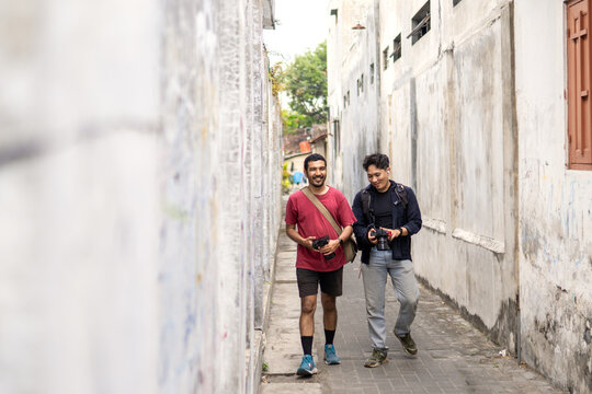 Two photographers walking and reviewing shots in a narrow alley