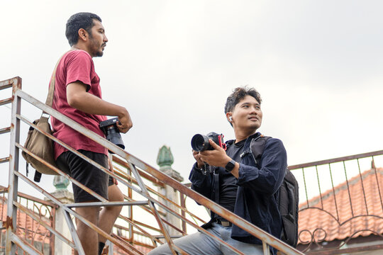 Two photographers walking and reviewing shots in a narrow alley - Powered by Adobe