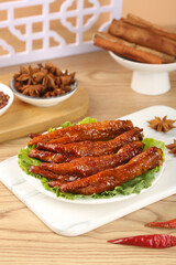 Traditional Asian marinated chicken feet with spices - glazed poultry delicacy snack served with star anise and cinnamon on wooden table