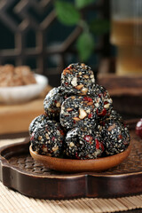 Black Sesame Seed Energy Balls with Nuts and Dried Fruits on Wooden Plate - Healthy Ready to Eat Snack