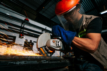 Metallurgy professional working with a grinder in the workshop. Man working with an angle grinder on a workbench in the workshop