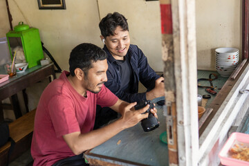 Two Indonesian Photographers Reviewing Camera Settings in a Local Cafe