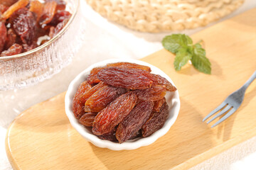 Tulufan Red Raisins from Xinjiang China in Bowl on Wooden Board with Fresh Mint
