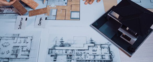 A collaborative scene showing diverse professionals engaging in architectural planning, with blueprints and a scale model laid out on a table for design analysis. SACTR