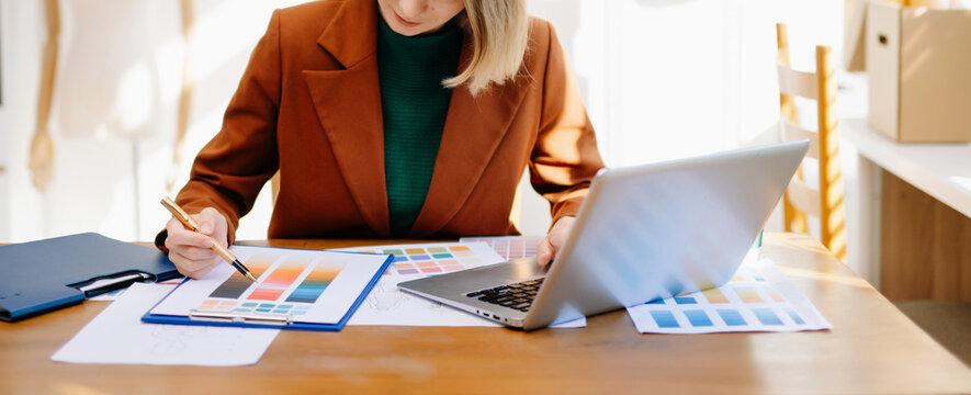Female designer choosing a color palette while working on a creative project in a bright modern workspace.