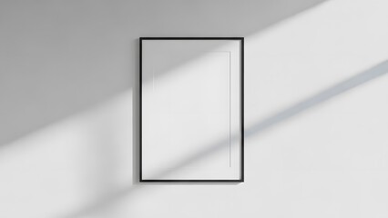 A clean and modern blank picture frame on a white wall with natural light shadows.