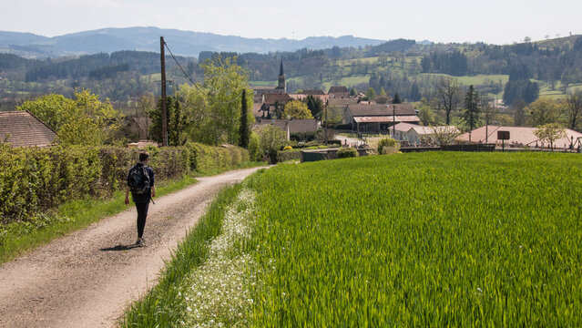 jeune gar&ccedil;on allant &agrave; pieds sur une route &agrave; un village en France, paysage rural fran&ccedil;ais en Sa&ocirc;ne-et-Loire