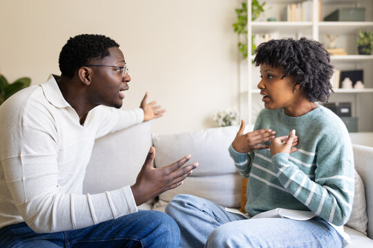 Young black couple arguing on sofa at home