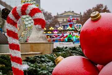 Christmas decorations with a white-red candy cane and large red baubles displayed on a snowy winter city square