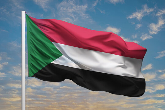 Realistic close-up of the Sudan flag waving on a tall flagpole under a bright sky with soft scattered clouds, showing smooth wind motion, vivid colors, and a strong atmosphere of national pride.
