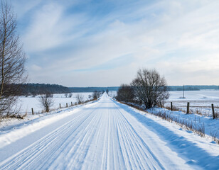 Long snowy country road stretching through peaceful winter farmlands