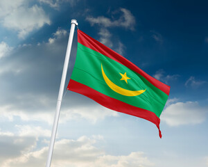 Realistic close-up of the Mauritania flag waving on a tall flagpole under a bright sky with scattered clouds, showing smooth wind motion, vivid colors, and a strong sense of national pride.
