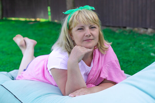 blonde woman in bright clothing relaxing outdoors on the lawn